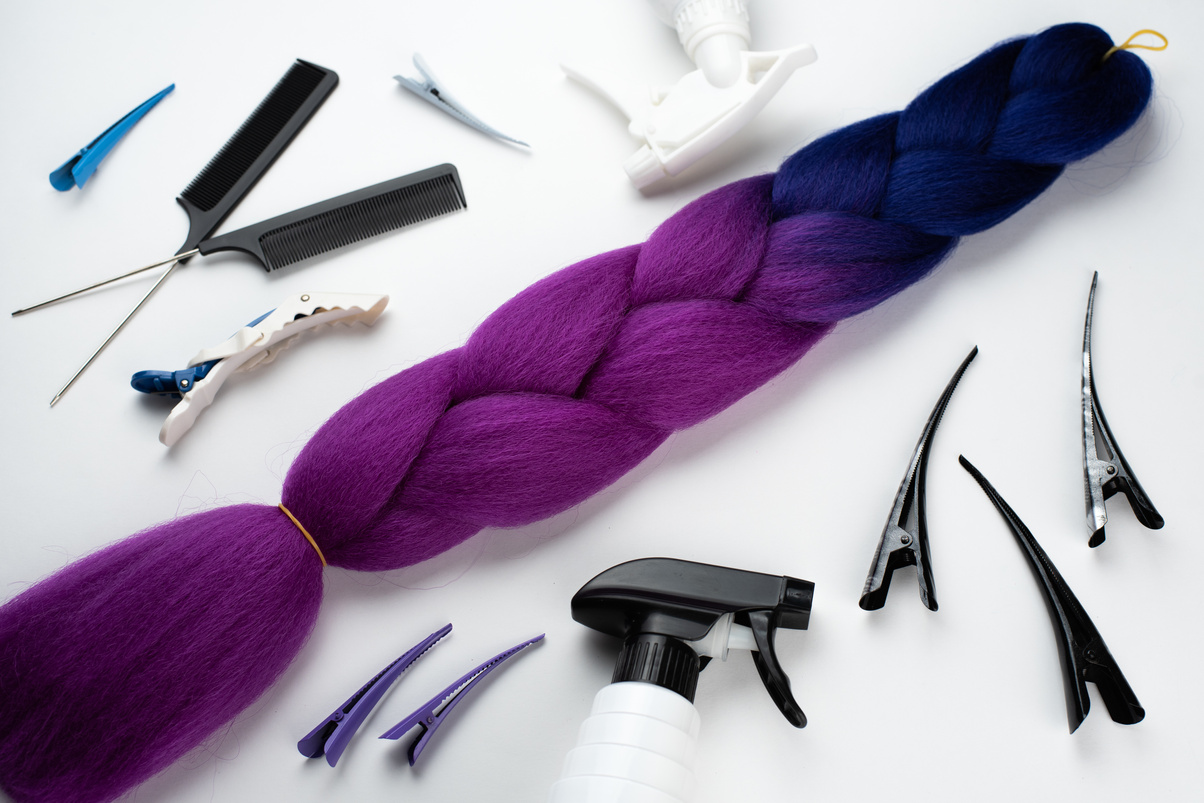 Kanekalon two- color-artificial hair purple and blue for braiding braids, lying on a white background next to accessories for braiding braids